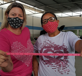 Equipe feminina composta por duas mulheres mostrando fita com frase de alusão ao outubro rosa da Afeec para o post Outubro Rosa da SME